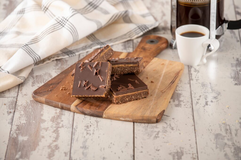 Chocolate caramel shortbread with chocolate topping on a wooden board.